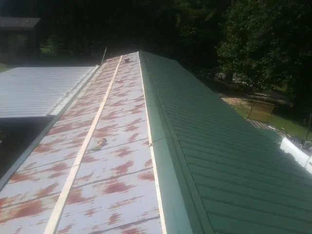 Old rusted panels beside newly installed green metal roofing — Wind Damage Roof Repair by Roofing Brothers in Crown Point