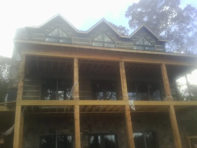 Dormers and porch framing on a large log home under construction — Roof Coating work by our crew in Crown Point