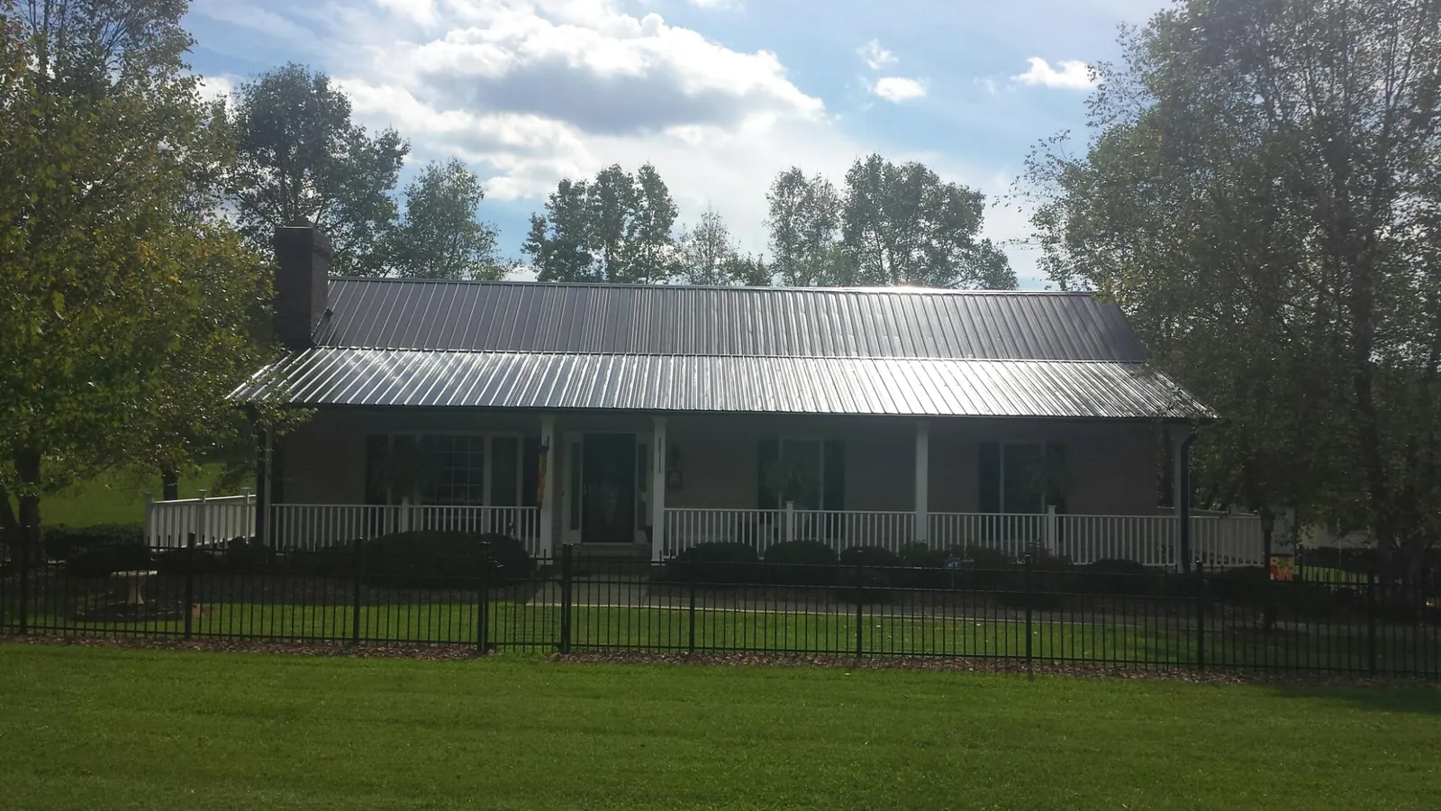Gray metal roof on a brick ranch with a full width front porch — Gutter Guard Installation work by our crew in Crown Point